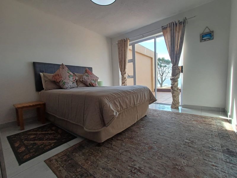 A bright bedroom featuring tiled flooring and a large sliding glass door that provides direct access to an outdoor balcony area.