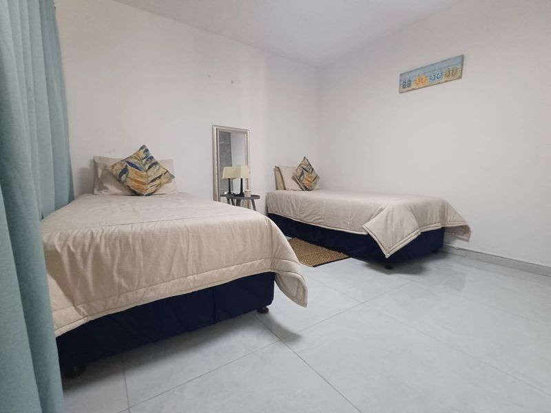 A simple bedroom featuring light-colored tiled flooring and neutral wall finishes, providing a clean and functional space.
