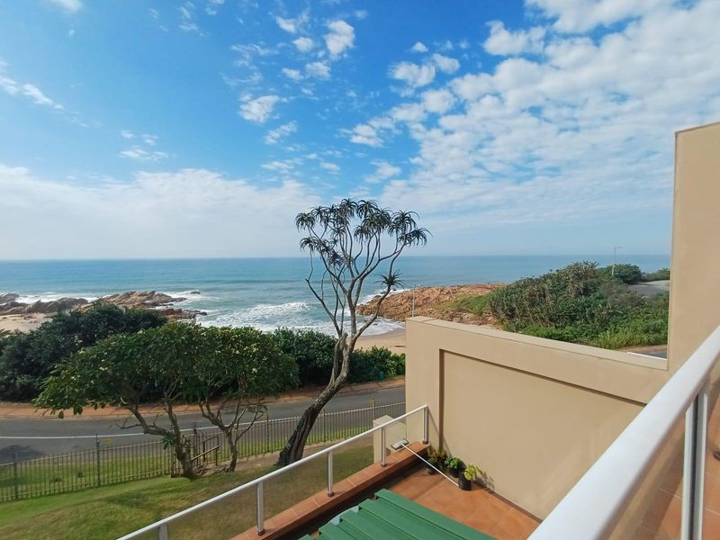 A scenic elevated view overlooking the coastline, beach, and ocean from a private balcony.