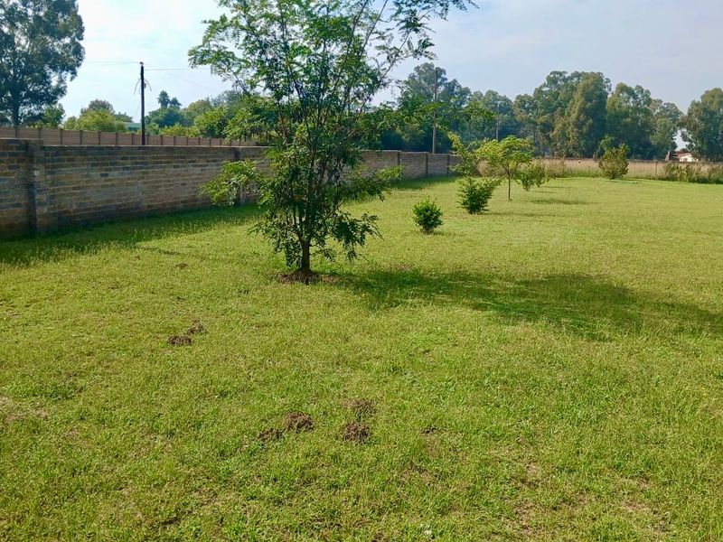 A spacious, level garden area featuring a well-defined perimeter brick wall and established lawn.
