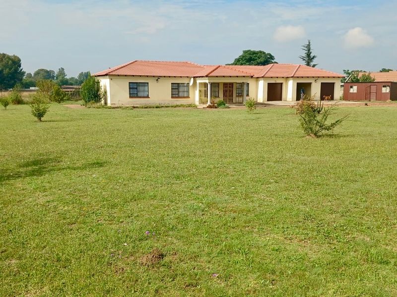 A single-story residential house featuring a tiled roof, double garage, and a spacious front lawn in a rural or semi-rural setting.