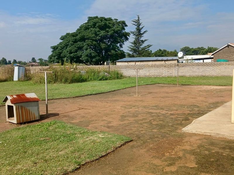 A spacious rear garden area featuring a concrete patio, brick boundary wall, and metal washing line poles, offering potential for landscaping and outdoor improvement.