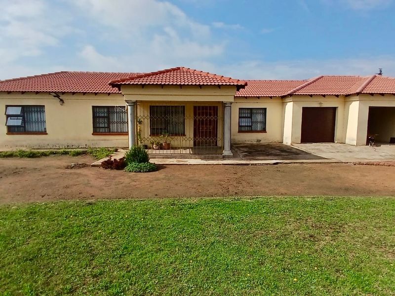Front elevation of a single-story house featuring a tiled roof, covered entrance porch with columns, and a triple garage with concrete driveway.