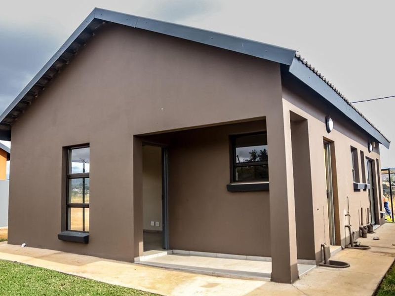 Rear view of a modern house featuring a covered patio, tiled roof, and aluminium window frames with a surrounding concrete apron.