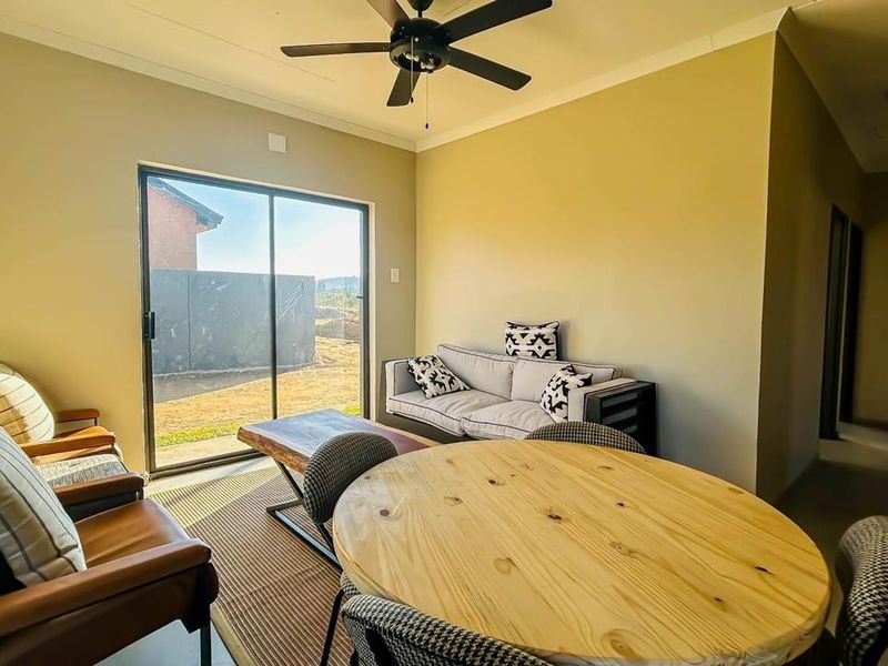 An open-plan living and dining area featuring tiled flooring, a ceiling fan, and a large sliding glass door providing access to the rear exterior.