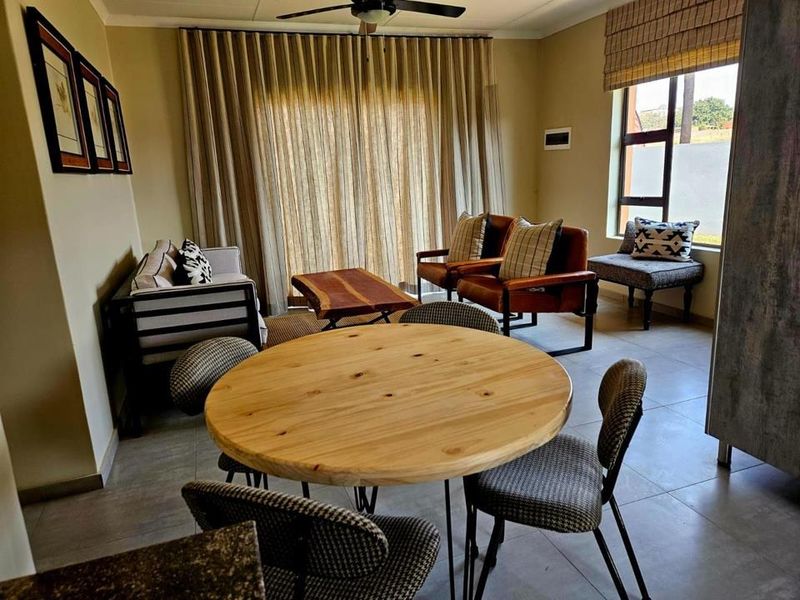 An open-plan living and dining area featuring tiled flooring, a ceiling fan, and large windows providing natural light.