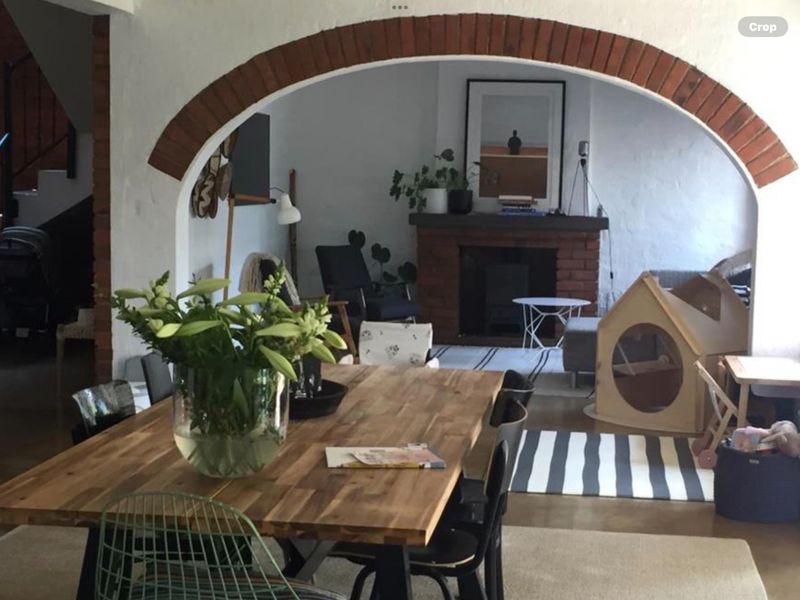 Open plan living and dining area featuring a distinctive brick archway and a traditional brick fireplace, creating a warm and character-filled space.