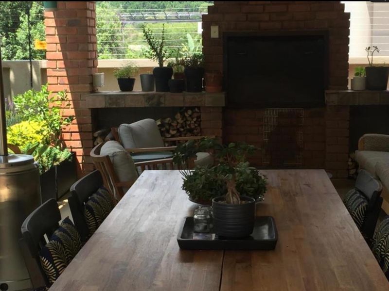Covered patio area featuring a substantial built-in brick fireplace with a stone hearth and integrated wood storage, ideal for outdoor entertaining.