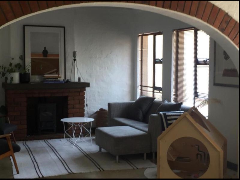 A cozy living room featuring a prominent brick fireplace with a wood-burning stove and a distinctive brick archway entrance.