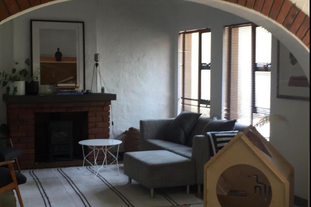 A cozy living room featuring a prominent brick fireplace with a wood-burning stove and a distinctive brick archway entrance.