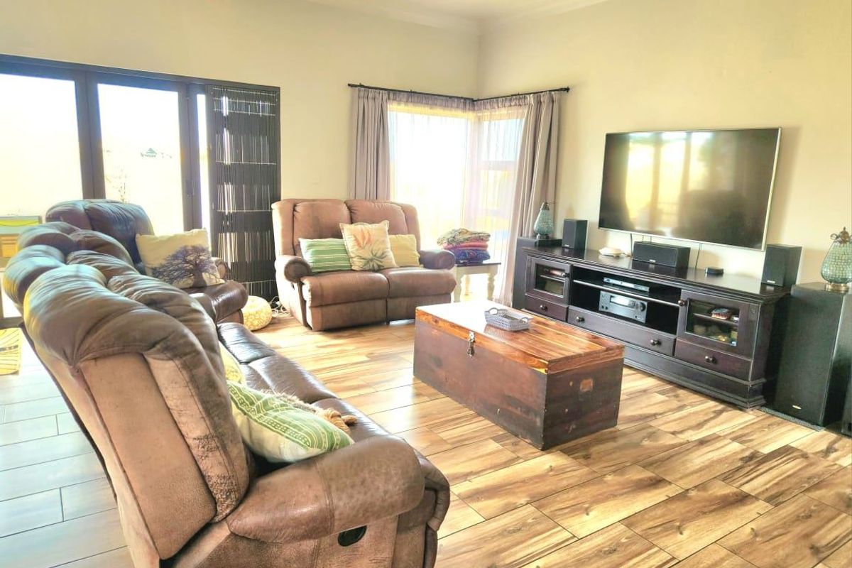 A comfortable living room featuring wood-look tile flooring, recessed lighting, and large sliding glass doors that provide ample natural light.
