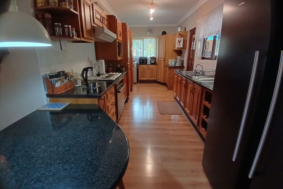 A functional kitchen featuring wooden cabinetry, granite countertops, and laminate flooring, offering a traditional aesthetic with ample storage and workspace.