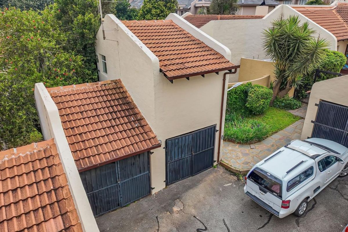 Aerial view of the property exterior featuring a double garage with terracotta tiled roofing and a paved driveway area.
