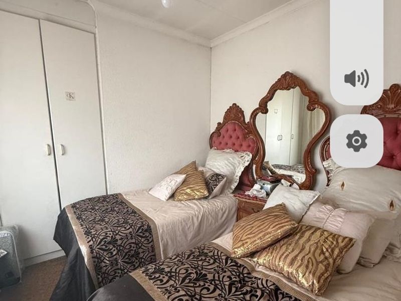 A bedroom featuring built-in wardrobes, coving, and carpet flooring, currently configured with twin beds.