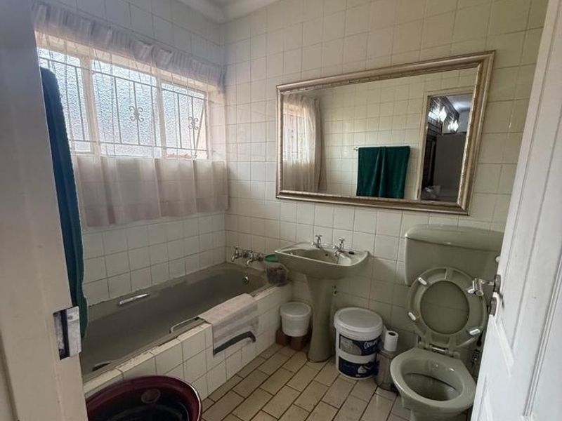 A dated bathroom featuring a bathtub, pedestal sink, and toilet with tiled walls and flooring, requiring modernization to improve its aesthetic and functionality.