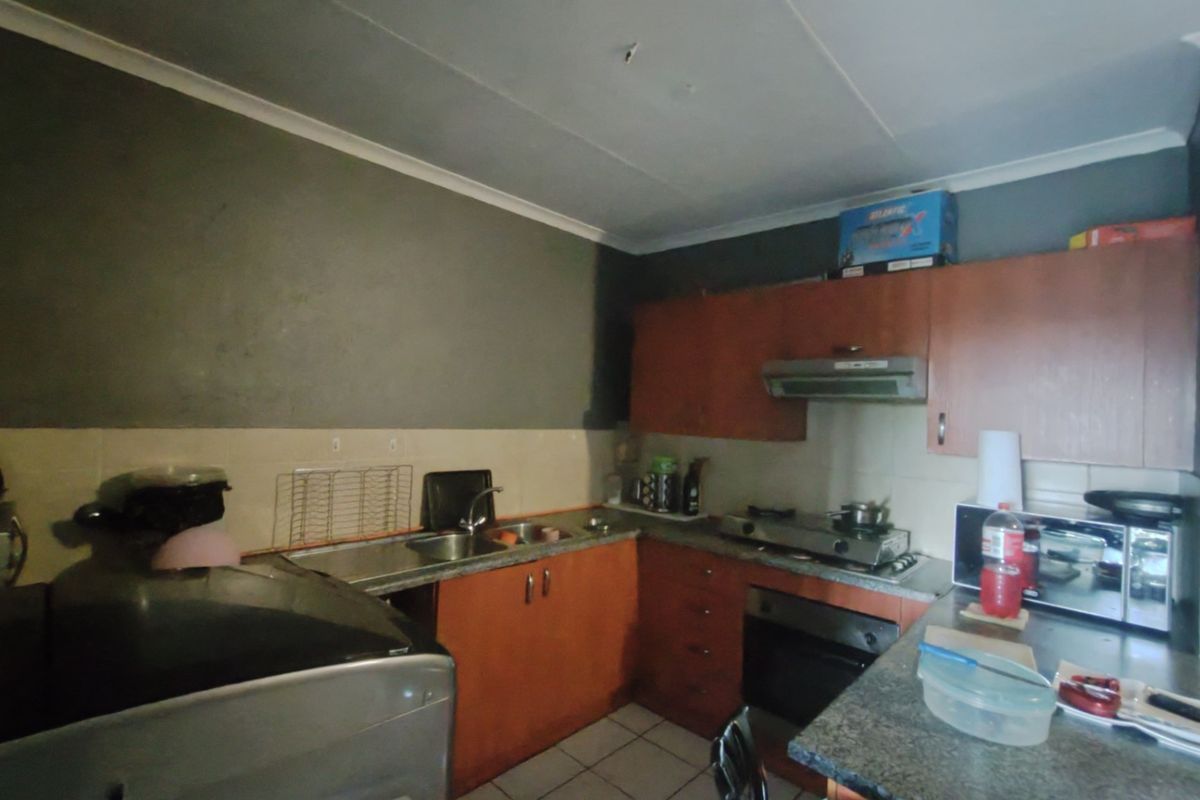 A functional kitchen featuring laminate cabinetry, built-in oven, gas cooktop, and tiled splashback, requiring cosmetic updates to improve its overall condition.
