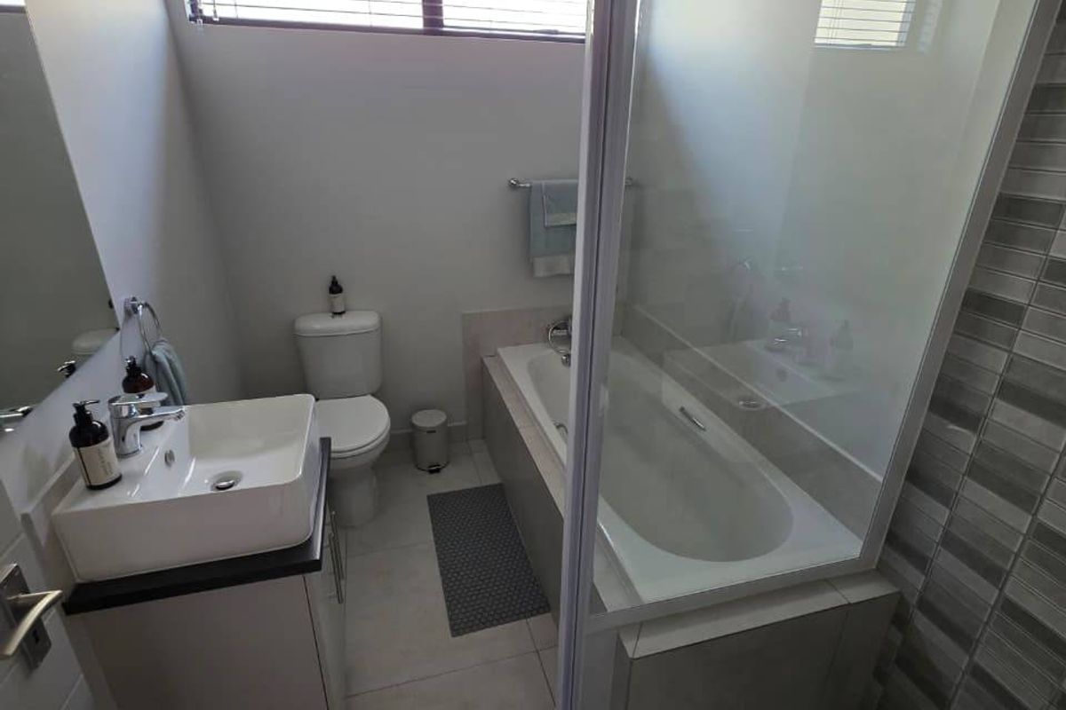 Modern bathroom featuring a vanity with basin, a separate built-in bathtub, and a glass-enclosed shower with decorative tiled wall accents.