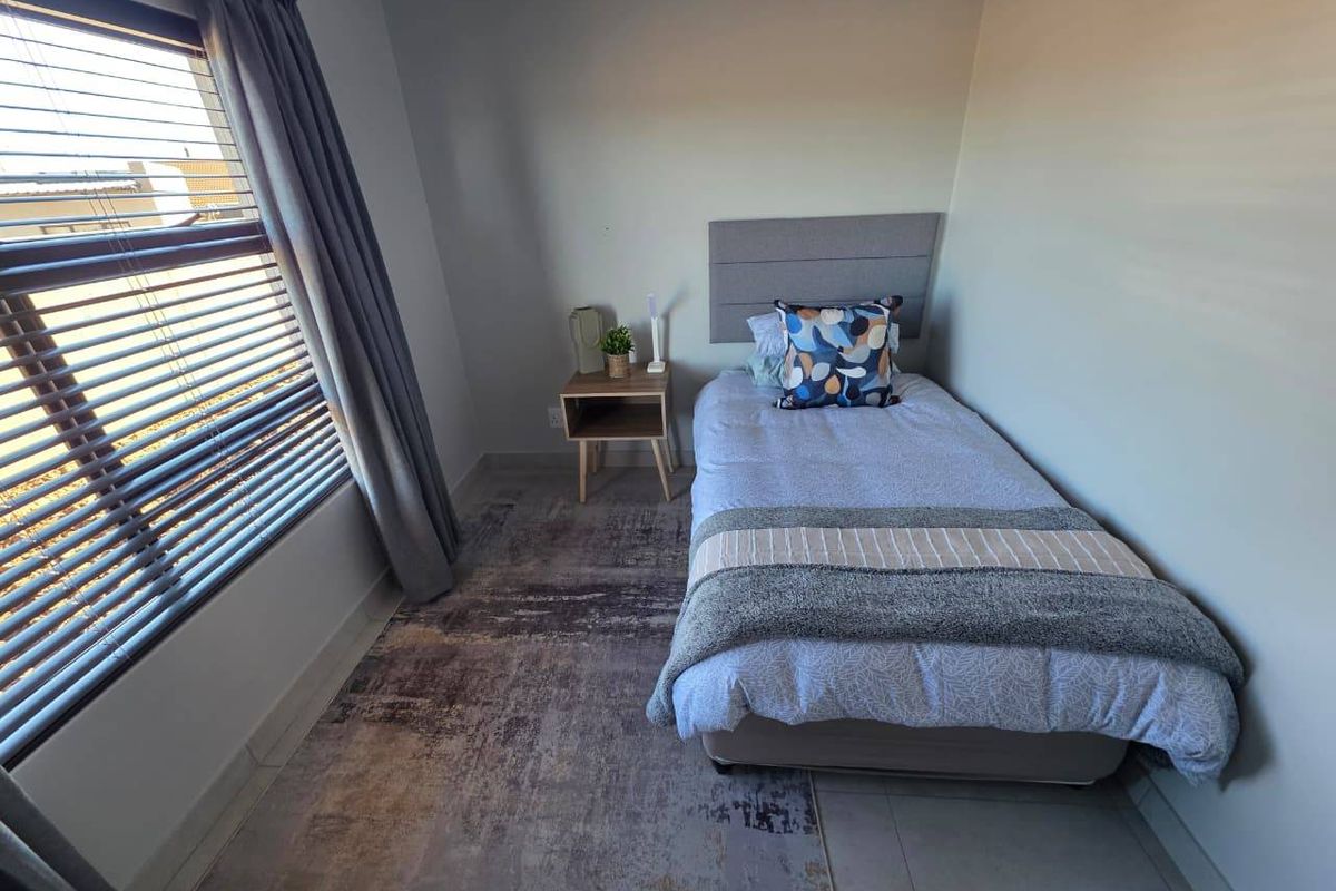 A well-lit bedroom featuring neutral wall tones, tiled flooring, and fitted venetian blinds, providing a comfortable and functional living space.