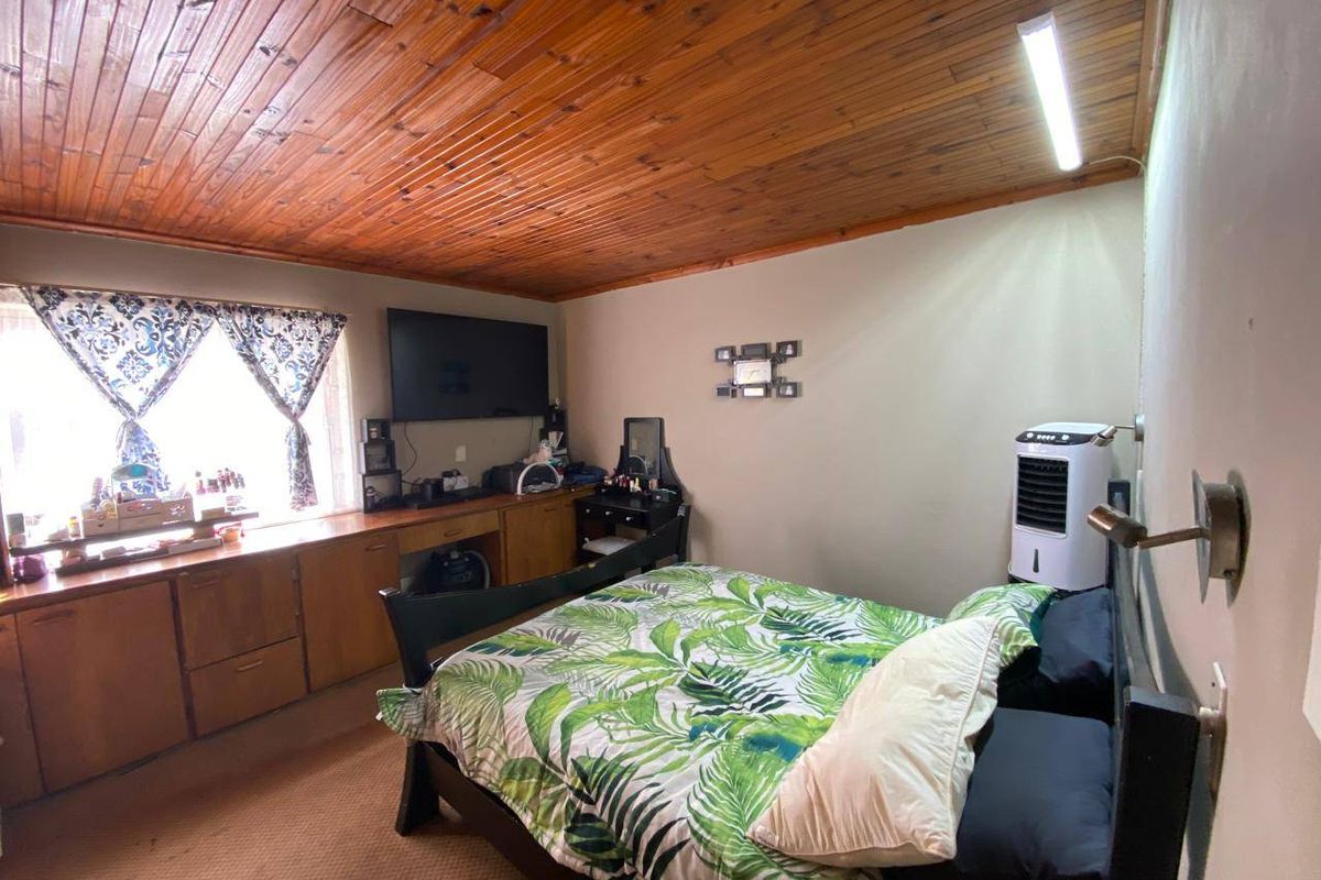 A bedroom featuring a timber tongue and groove ceiling and built-in cabinetry providing ample storage space.