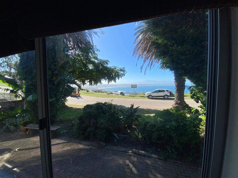 A view of the ocean and coastline framed through a sliding glass door from an interior space.