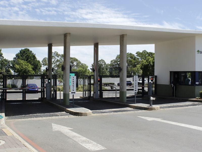 The main entrance and security gatehouse of the Green Park apartment complex, featuring controlled access boom gates and a modern structural canopy.