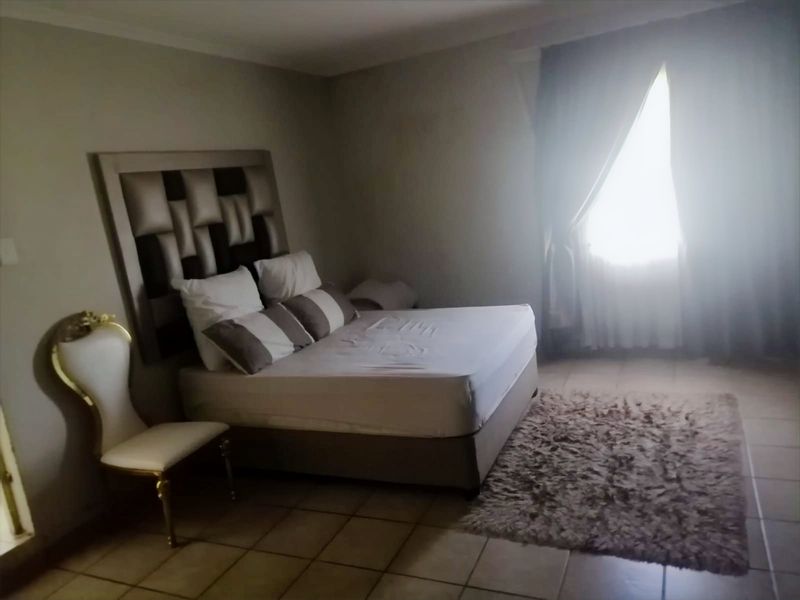 A bedroom featuring tiled flooring and natural light from a window with curtain rails.