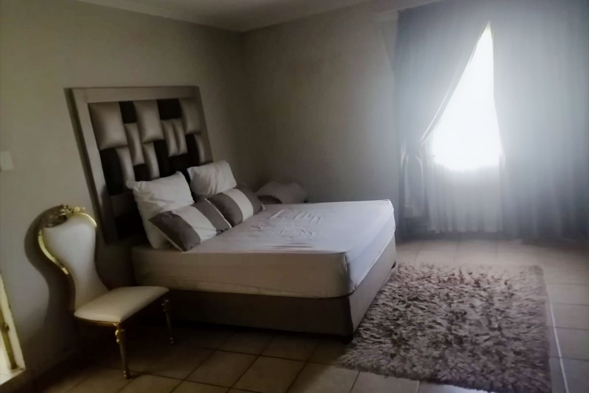 A bedroom featuring tiled flooring and natural light from a window with curtain rails.