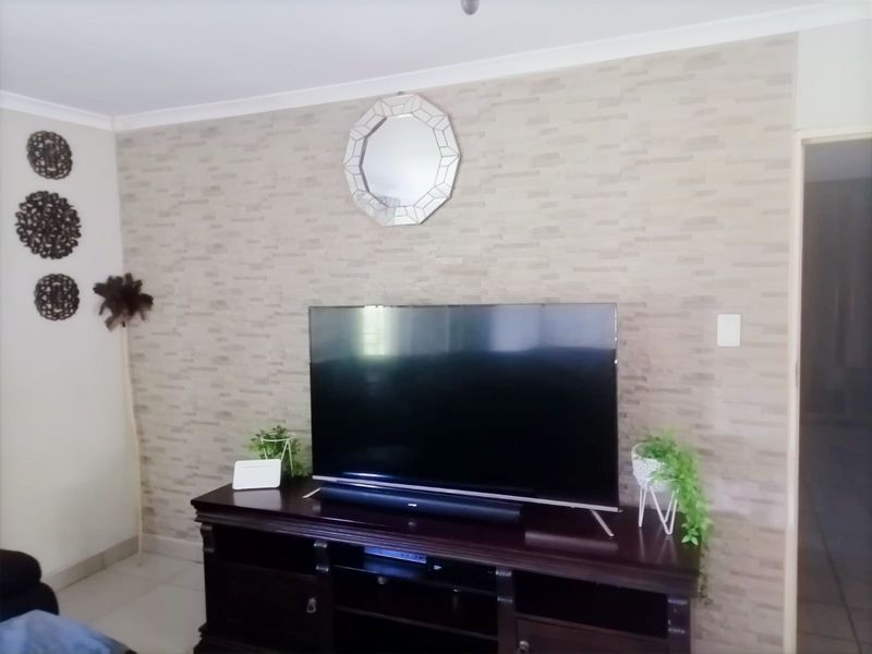 A living room featuring a textured accent wall and coved ceiling, providing a neutral backdrop for entertainment.