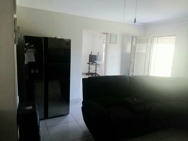 A living room area featuring tiled flooring and access to an exterior doorway with a security gate.