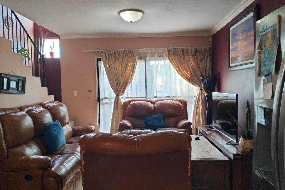 A living room featuring tiled flooring, a staircase with metal railings, and a sliding glass door providing access to the exterior.