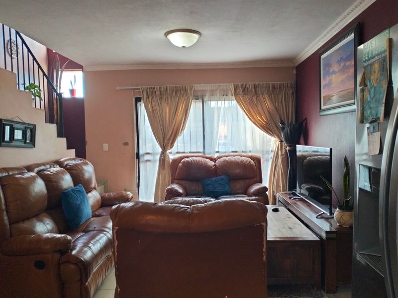 A living room featuring tiled flooring, a staircase with metal railings, and a sliding glass door providing access to the exterior.