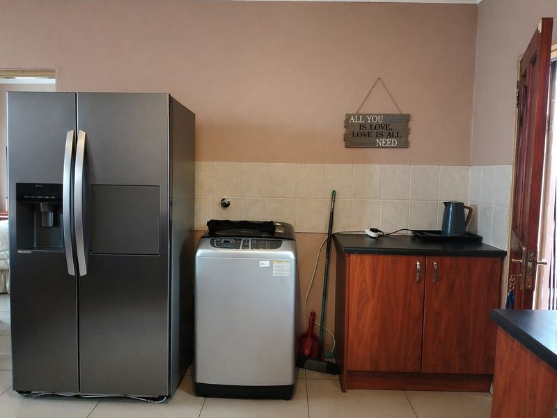 A functional laundry area featuring tiled splashbacks, built-in cabinetry with laminate countertops, and dedicated plumbing connections for appliances.