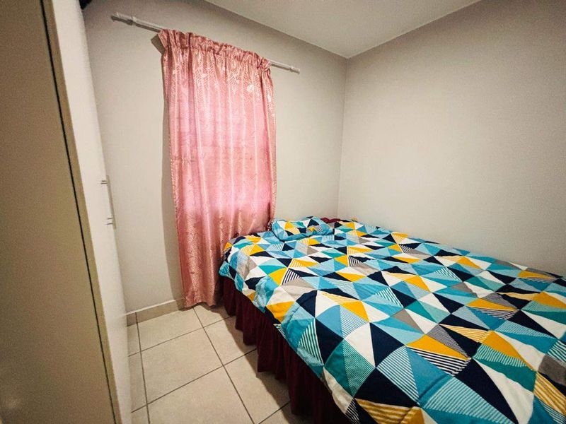 A compact bedroom featuring tiled flooring and a built-in wardrobe, providing functional storage space.