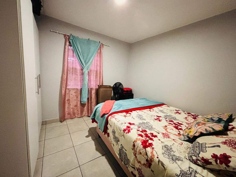 A functional bedroom featuring tiled flooring and a built-in wardrobe, providing essential storage space.