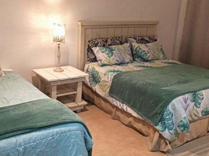 A bedroom featuring a double bed and a single bed, with neutral wall finishes and floor-to-ceiling curtains.