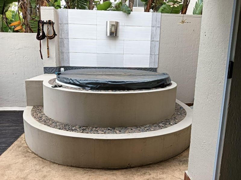 Outdoor area featuring a circular built-in jacuzzi with a tiled feature wall and pebble inlay detailing.