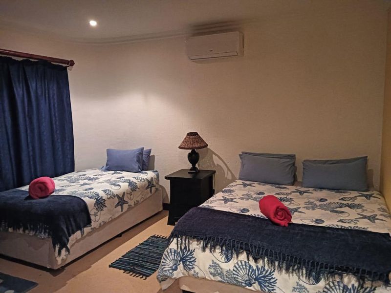 A bedroom featuring a wall-mounted air conditioning unit and recessed ceiling lighting.
