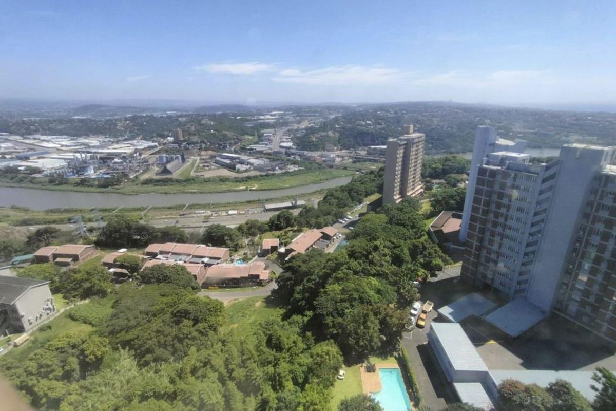 Elevated aerial view overlooking the surrounding urban landscape, river, and residential apartment complex with a swimming pool.