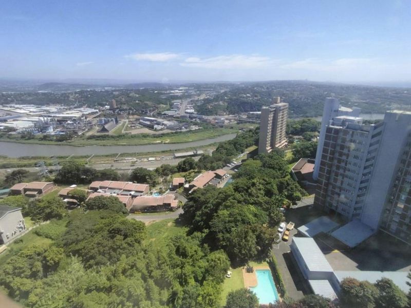 Elevated aerial view overlooking the surrounding urban landscape, river, and residential apartment complex with a swimming pool.