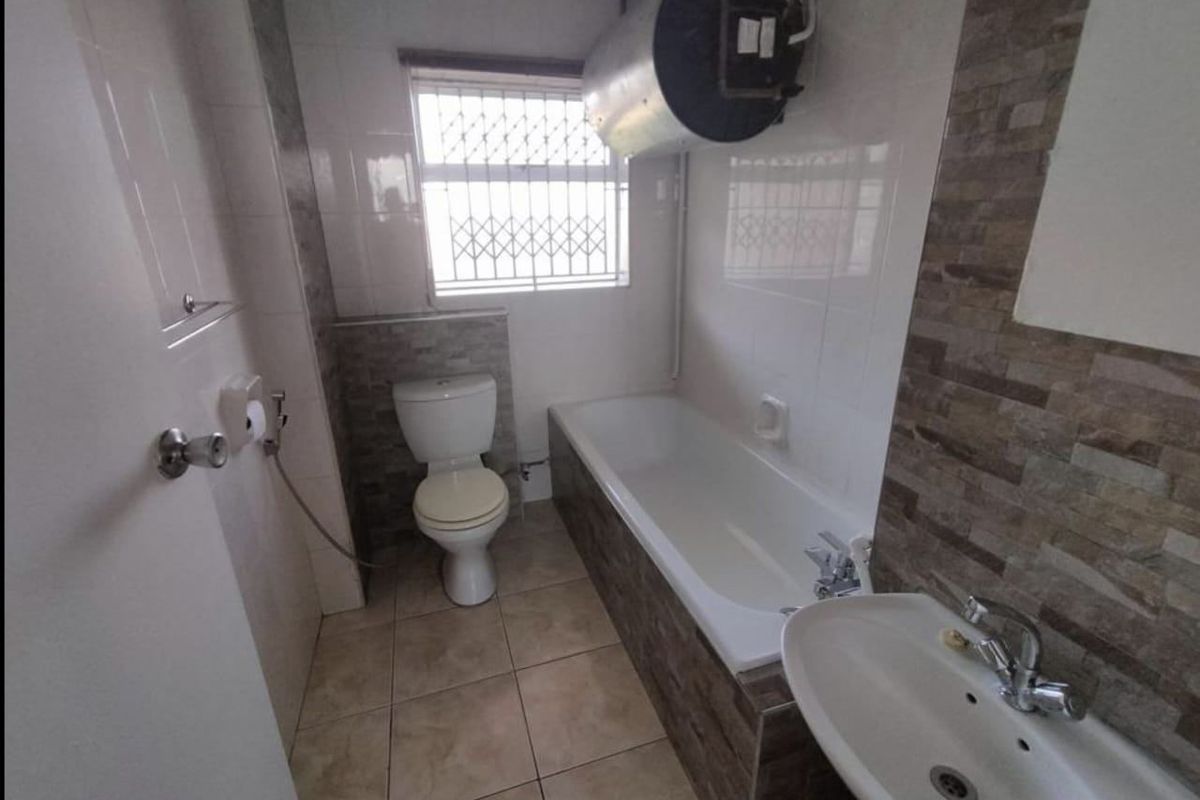 A functional bathroom featuring a bathtub, pedestal basin, toilet, and an exposed wall-mounted water heater.