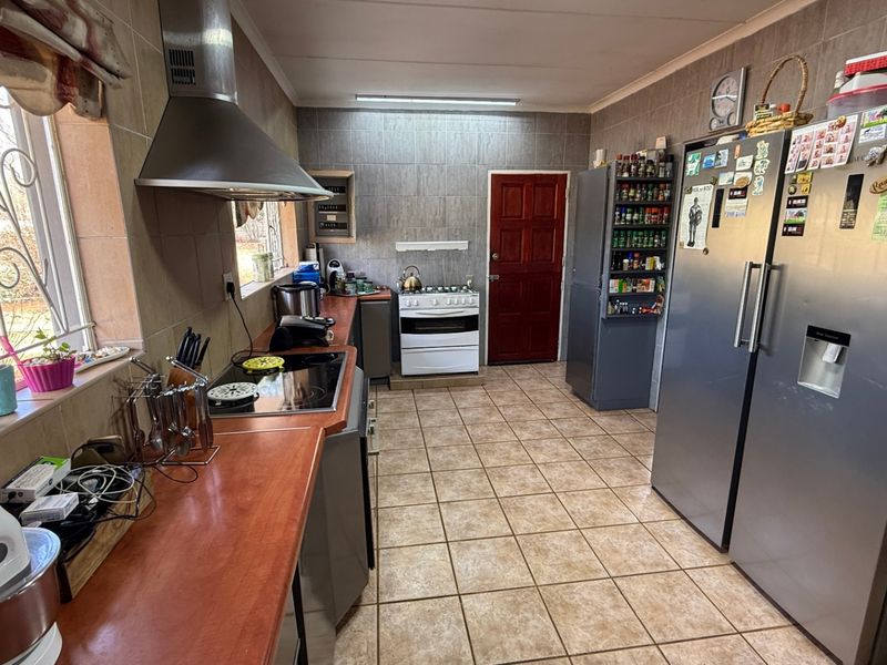 A functional kitchen featuring tiled walls and flooring, laminate countertops, a built-in stove, and an extractor fan.