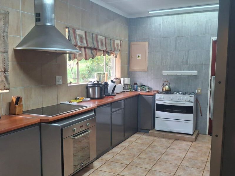 Functional kitchen featuring fitted cabinetry, laminate countertops, tiled splashbacks, a built-in oven, and a stainless steel extractor fan.