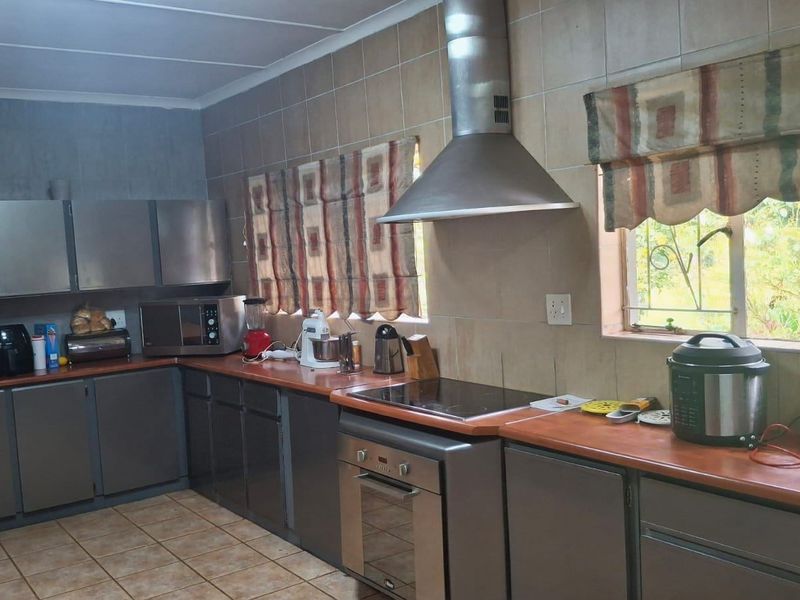 A functional kitchen featuring built-in cabinetry, an electric hob, an extractor fan, and tiled splashbacks, offering a practical layout for daily meal preparation.
