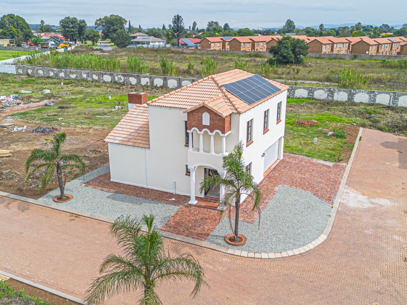 Aerial view of a two-story residential property featuring a tiled roof with solar panels, a brick driveway, and a balcony.