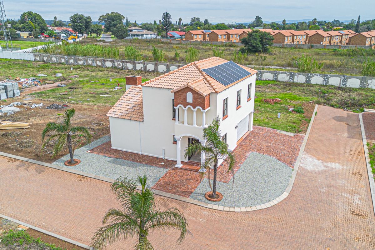 Aerial view of a two-story residential property featuring a tiled roof with solar panels, a brick driveway, and a balcony.