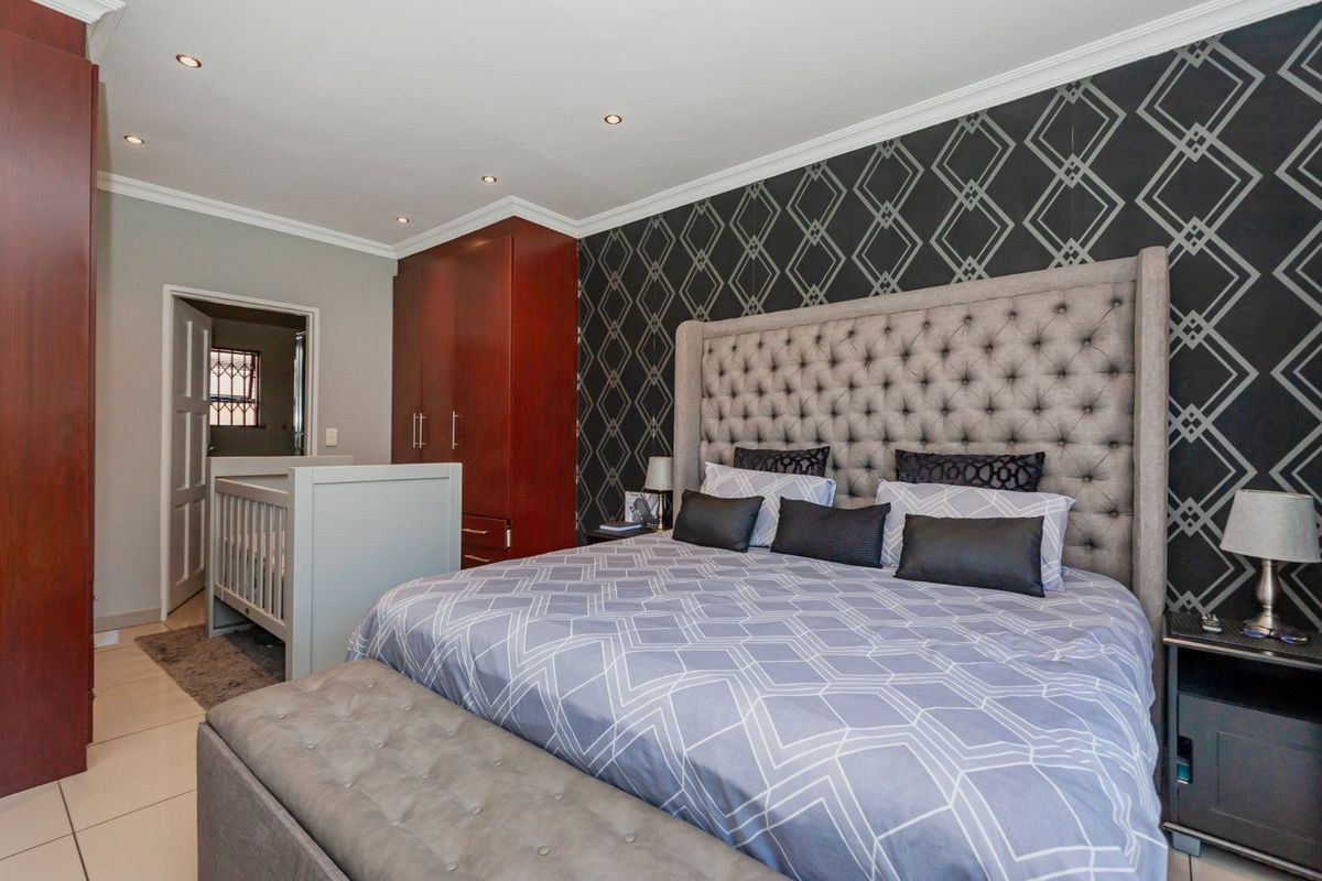 Spacious bedroom featuring built-in cupboards, tiled flooring, and recessed downlighting, offering a comfortable and well-maintained living space.