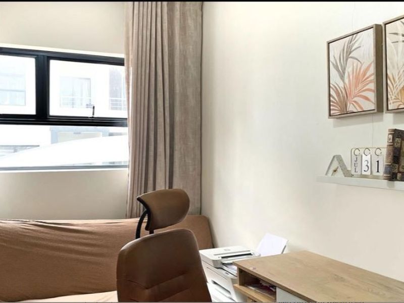 A functional home office space featuring a large window with modern black aluminium frames and neutral curtains, providing natural light to the workspace.