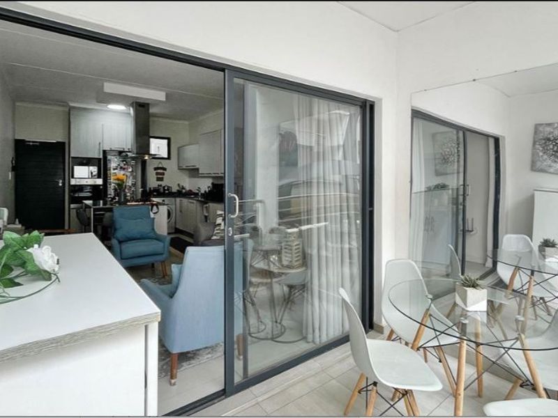 A covered balcony area featuring tiled flooring, large sliding glass doors providing access to the interior, and a decorative mirrored wall.
