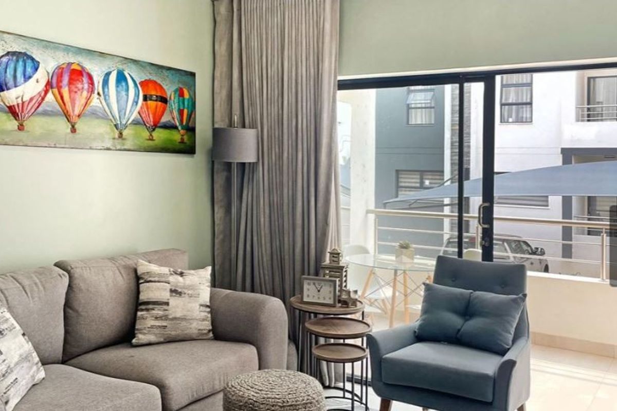 A well-lit living room featuring large sliding glass doors that provide access to an outdoor balcony area.