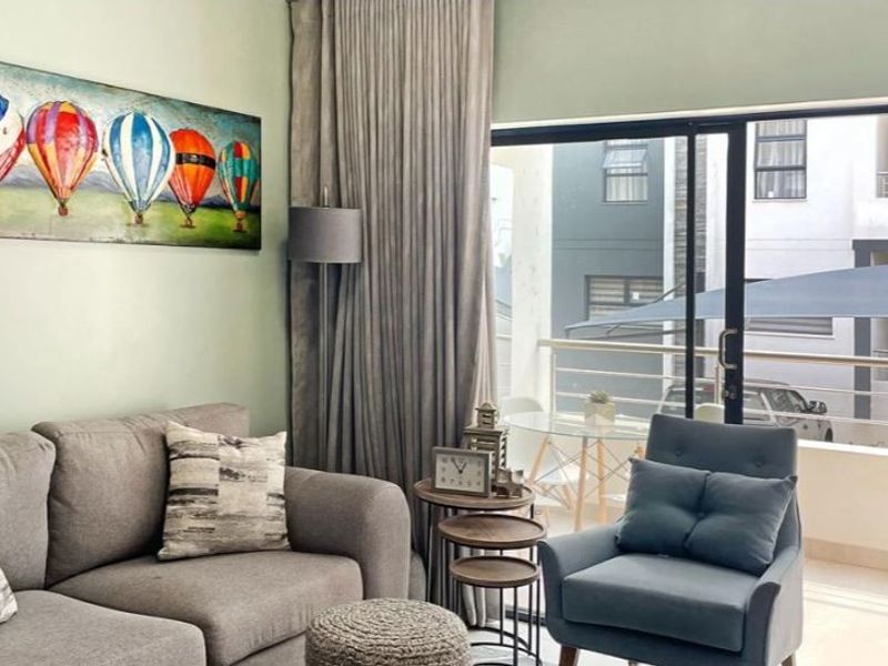 A well-lit living room featuring large sliding glass doors that provide access to an outdoor balcony area.